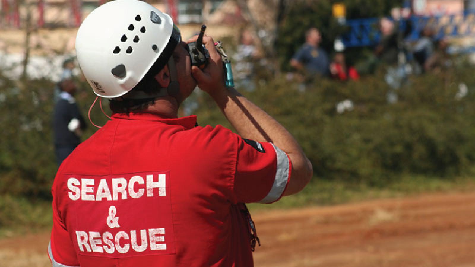 Photo of first responder in rural dirt field talking on a walkie talkie