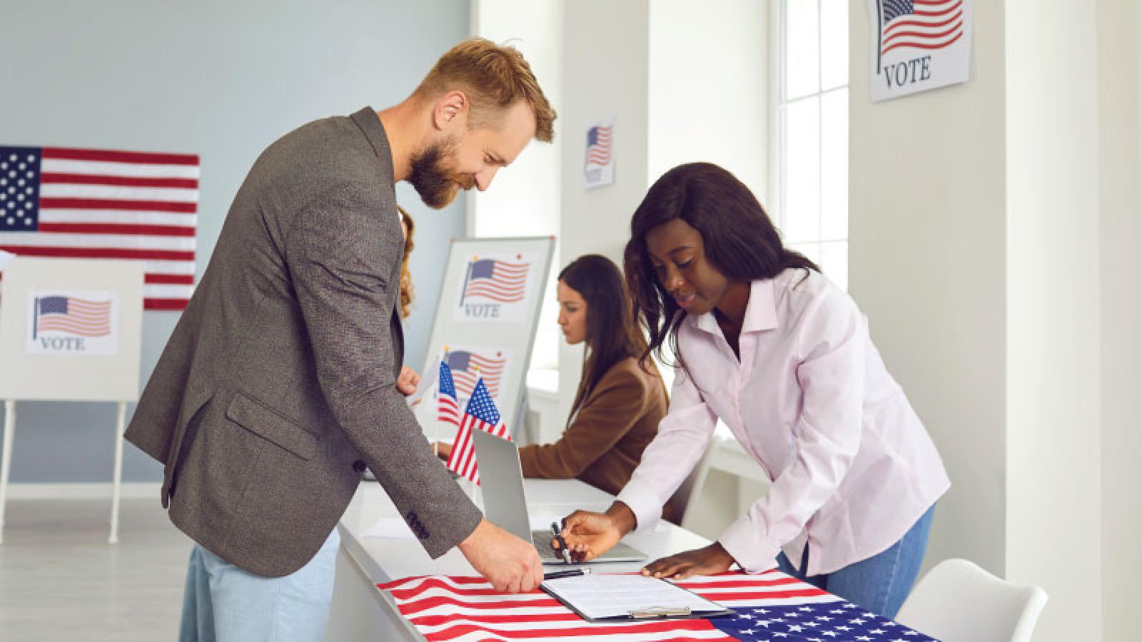 Photo of poll worker assisting line of voters