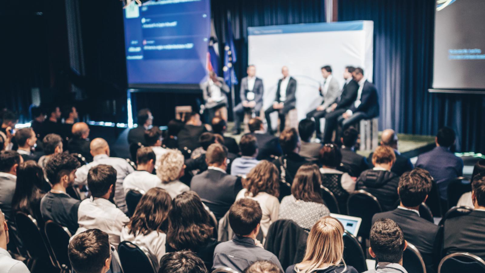 Group of professionals talking on a panel at a conference