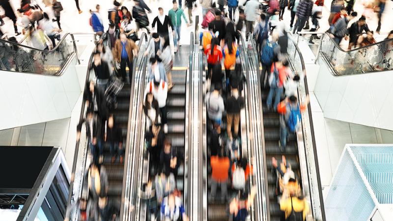 Crowds of people riding escalators. 