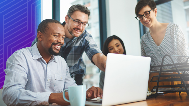 Colleagues gathered around a computer learning about cybersecurity.