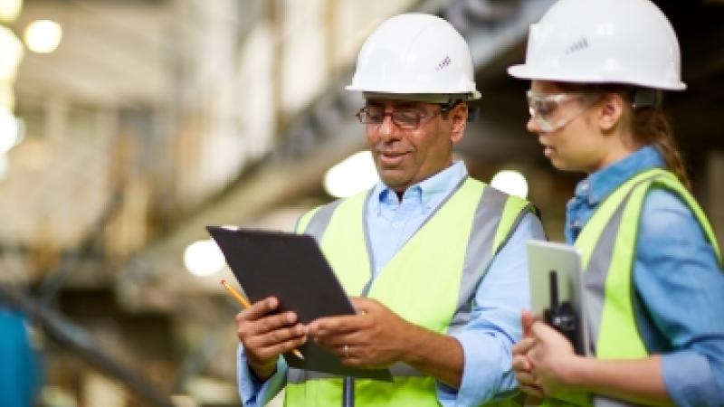 Two individuals at a chemical facility looking at content on a clipboard