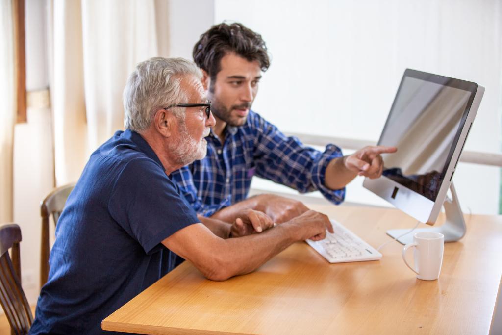 Man showing elderly man how to use the computer