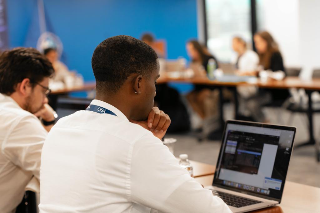 Male intern at computer working on exercise with other interns in the background.