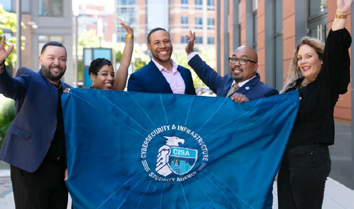 CISA Employees smiling with the CISA flag